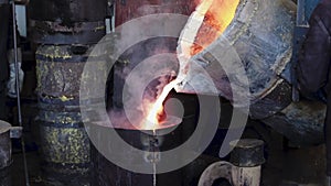 Foundry production. Workers pour metal from the bucket into special molds