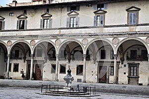 Fountain and beautiful historical facade of the building located in the Piazza della Santissima Annunziata in Florence.