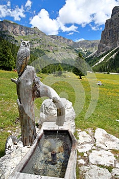 A fountain with a carved wooden owl along Vallunga Valley above Selva, Val Gardena