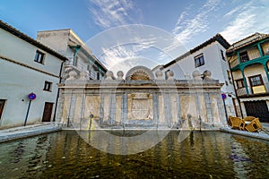 Fountain in the central square of the town of Chinchon in Madrid, typical houses with wooden balconies and an old medieval