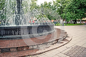 Fountain in city park on summer day. stream of water, drops and bright splashes of water in beautiful city fountain