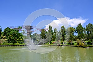 Fountain and dragonfly sculptures made of metal in pond at Gardens by the Bay, Singapore. Supertrees in the back. photo