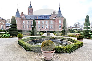 Fountain in French garden with Alden Biesen castle in background