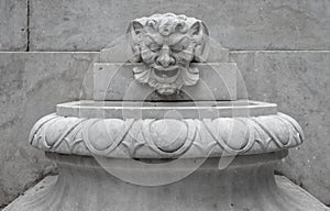 A fountain with a head carved in stone.