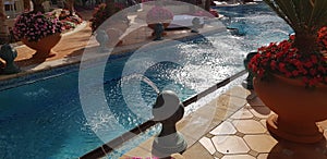 Fountain jets into the water canal of blue outdoor swimming pool