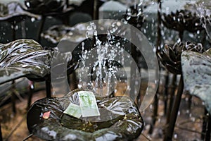 Fountain in a park in Hong Kong temple in which people throw coins and notes for luck