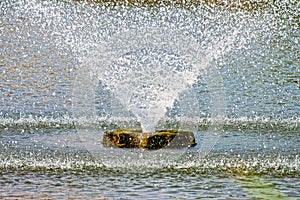 Fountain in park pond explodes like a volcano of water and falls back in a circle of spray - Motion blur and close-up