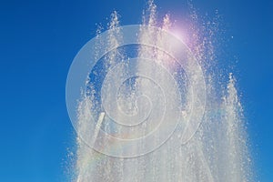Fountain in the Park with water jets and splashes against the blue sky on a Sunny summer day