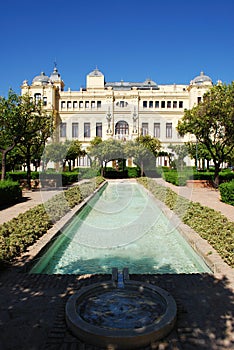 Fountain in the Pedro Luis Alonso gardens with the city hall to the rear, Malaga, Spain.