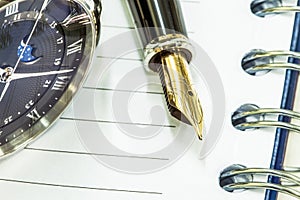 Fountain pen on blank notepad and watch