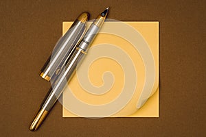 A fountain pen and blank yellow sticky note waiting for your message