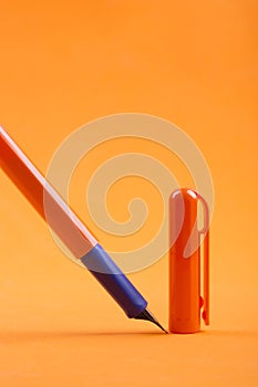 Fountain pen with a cap on an orange background.