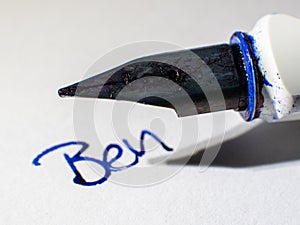 Fountain pen close-up writing Ben in blue letters on a white paper