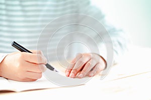 Fountain pen holding by man with small notebook on desk