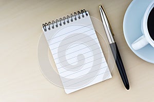 Fountain pen, notepad and cup of coffee on wooden background