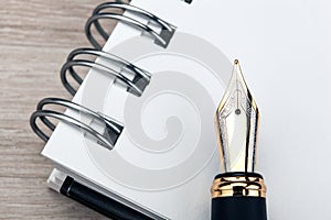 Fountain pen on the notepad on a wooden table