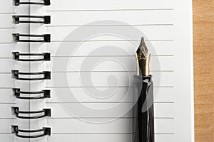 Fountain pen resting on a lined notebook with metal rings