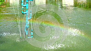 Fountain pipe in the pond and rainbow on water surface
