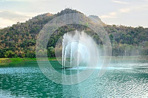 The fountain in the public park has a mountain background. photo