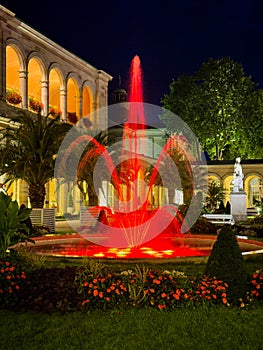 Fountain with red lights in Bad Kissingen Kurpark Park at night.