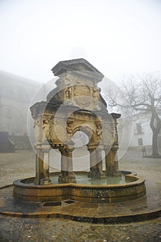 Fountain of Saint Mary -Santa Maria- and st. Philip seminary a foggy day in Baeza. Spain