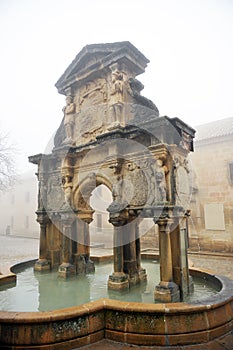 Fountain of Saint Mary -Santa Maria- and st. Philip seminary a foggy day in Baeza. Spain