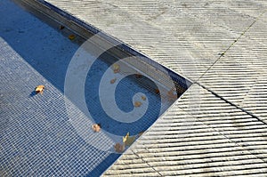 Fountain in the square lined with a mosaic of tiles. through a science terrace or bridge made of metal stainless steel slats. the