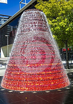 Fountain from stones in form of cone or tower or pyramid in red-orange color.