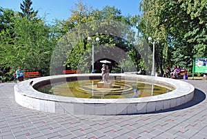 The fountain in the Strukovsky garden with the established bronze sculpture of the boy and girl under an umbrella in the sunny day