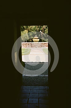 Fountain in sunshine outside darkened doorway