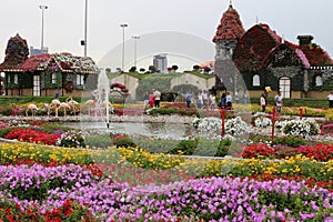 fountain surrounded with colorful flowers