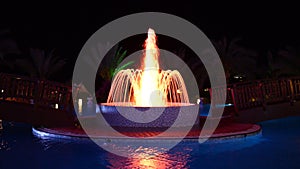 The fountain in swimming pool at luxury hotel in night illumination