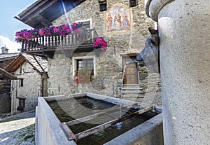 Fountain and typical houses of wood and stone, Antagnod, Aosta Valley, Italy photo