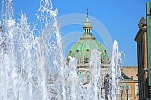 Fountain of water with Amalienborg Palace Square and a statue of Frederick V on a horse in the background, Copenhagen, Denmark