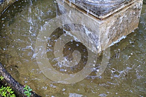 Fountain water stream splashing in the middle of the old marketplace. An old classic style stone