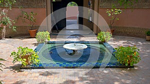 Fountain with zellige and potted plants in the Jardin Majorelle in Marrakesh, Morocco.