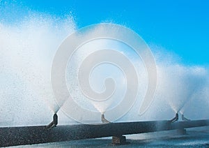 Fountains from a system of pipes cooling water at a thermal power plant. Splashing fountain against blue sky in industrial area