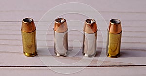 Four 40 caliber hollow point lined up on a white wooden back ground