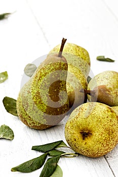 Four abate fetel pears with leaves on white painted wood.