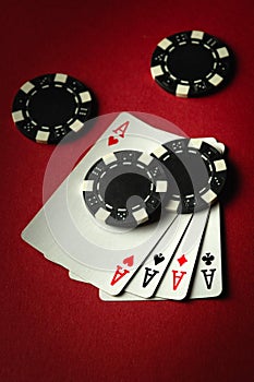 Four aces and black chips on a red table in a casino. Concept of winning with a four of a kind or quads combination in a poker photo