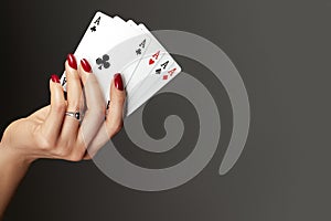 Four aces playing cards in woman`s hand. Player with poker quads combination. Elegant female hands with red manicure