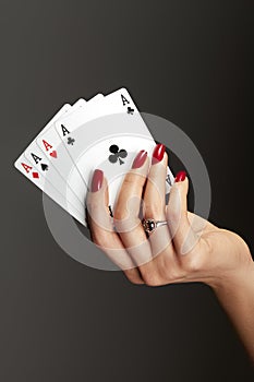 Four aces playing cards in womans hand. Player with poker quads combination. Elegant female hands with red manicure