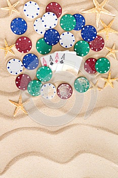 Four aces with poker chips on beach sand