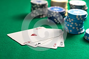 Four aces and poker chips on green felt background