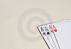 four aces poker hands playing cards on a light desk background.