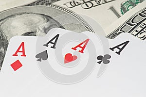 Four aces poker playing cards among U.S. dollars