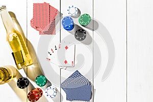 Four aces surrounded by poker chips and beer on white wooden background and copy space