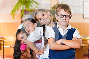 Four adorable schoolchildren standing in classroom photo