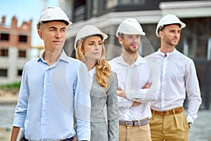 Four adult people in hardhats standing on the building site