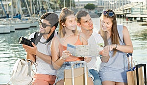 Four adult travelers holding map in hands